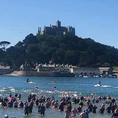 Group of swimmers entering the water in front of St Michaels mount